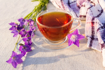 Cup of tea on checkered napkin and blue bell flowers