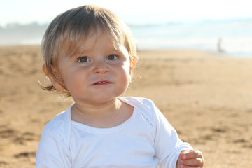 Happy blond baby playing at the beach