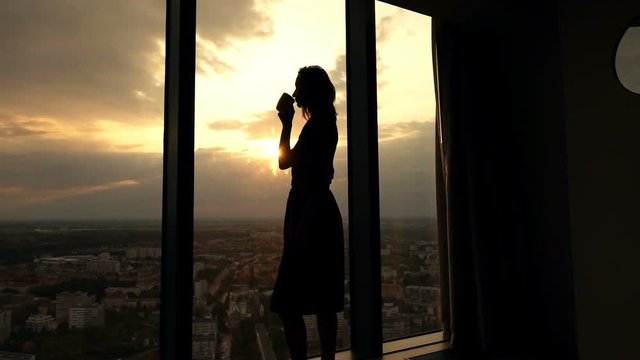 Woman drinking coffee by window during sunset, super slow motion 240fps
