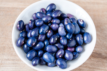 In a white plate, blue bean stands on table
