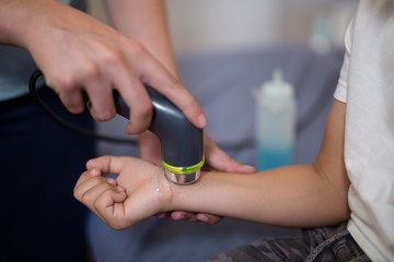 Close-up of female therapist using ultrasound machine on wrist