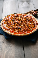 Pumpkin pie with oat pecan crust over wooden background. 