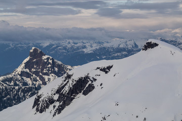 Aerial landscape view of beautiful mountain range with cloud layers during sunset. Taken in a remote area North of Sunshine Coast, British Columbia, Canada.