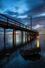 Fototapeta premium Beautiful sunset at the beach by the wooden quay. Taken in Blackie Spit, Whiterock, Greater Vancouver, British Columbia, Canada.