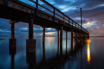 Beautiful sunset at the beach by the wooden quay. Taken in Blackie Spit, Whiterock, Greater Vancouver, British Columbia, Canada.