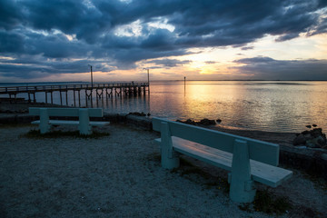 Benches in front of a beautiful sunset at the beach by the wooden quay. Taken in Blackie Spit, Whiterock, Greater Vancouver, British Columbia, Canada.