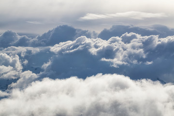 Fototapeta premium Above the clouds view of different cloud formations covering the remote mountains of British Columbia, Canada. Can be used for background.