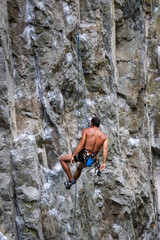 Rock climber resting while hanging on a steep rock face in Squamish, British Columbia, Canada.