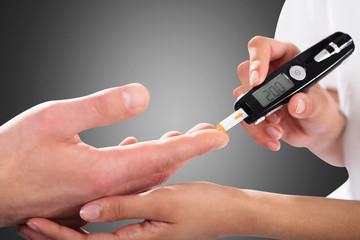 Person Checking Blood Sugar Level By Glucometer