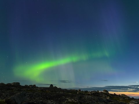 The Aurora in the sky above the hills at night .