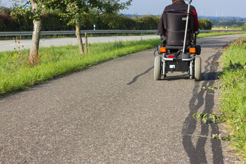 motor-driven wheel chair on a street in september fall