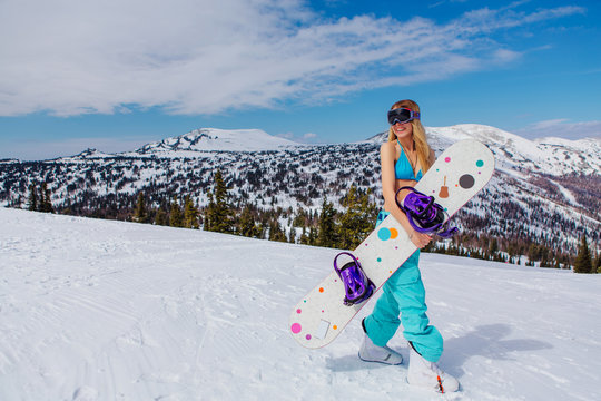 Young woman in swimsuit with snowboard on the slope