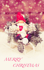 Wooden doll on icy sledge with gifts. Christmas card.