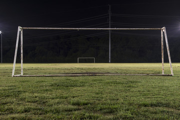 Empty soccer field at night through goal without net