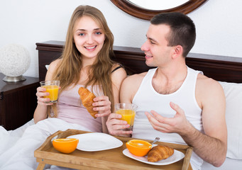 Couple with tasty breakfast in bed.