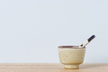 Ceramic bowl and ceramic spoon on wooden table