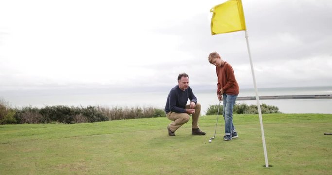 Father watching Son play golf