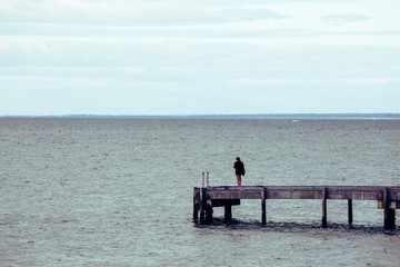海の桟橋に立っている女性