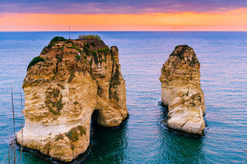 Obraz premium Piękny zachód słońca na Raouche, Pigeons 'Rock. W Bejrucie w Libanie Słońce i kamienie odbijają się w wodzie, gęste chmury na niebie.