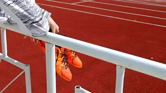 Track runner with shoes in hand looking the stadium, 4k