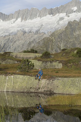 Fototapeta na wymiar Hiker makes a break at a mountain lake in the Alps in Switzerland