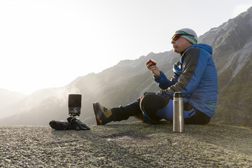 Hiker eats an apple during a break and prepares a hot tea