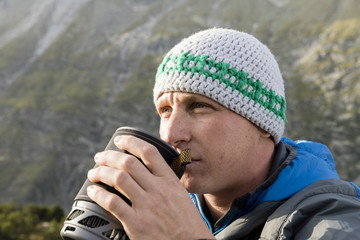 Alpinist strengthens himself with a hot tea during a strict mountain tour