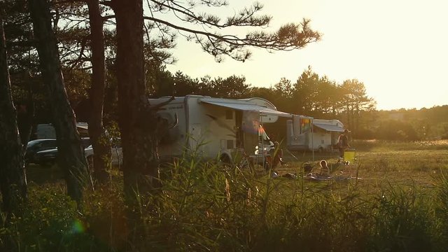 Sunset at campsite, modern caravan camper. Family adventure trip during holiday vacation time in wilderness area. Road trip