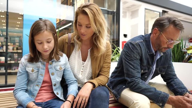 Family on shopping day in mall, sitting on public bench