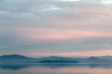 A lake at dusk, with beautiful, warm tones in the sky and water