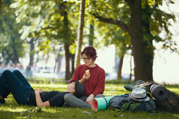 Couple of teenagers tourists with backpacks have rest in the city park