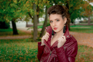 Молодая девушка в кожаной курте в осеннем парке. - obrazy, fototapety, plakaty