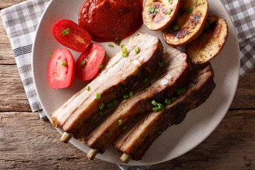Baked pork brisket with potatoes and sauce close up. horizontal top view