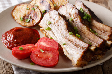 Fried hot pork ribs with sauce and baked potatoes close up. horizontal