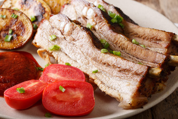 Fried pork ribs with sauce and tomatoes on a plate close up. horizontal