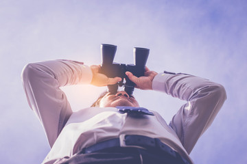 Businessman looking through binoculars. low angle view.