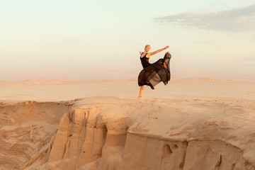 Dancer jumped while dancing, she was in the desert of their sand. © Petro