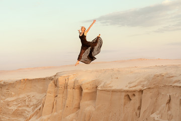 Woman while dancing jumped into the abyss with the dune sand. © Petro