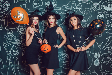 Beautiful girls in witches costumes on a dark background with a picture. Halloween.