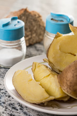 Cooked potatoes on the plate with salt and pepper and bread