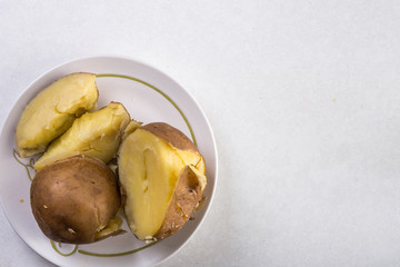 Flat lay above served cooked potatoes above white marble background