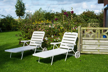 Zwei weiße Liegestühle im Garten