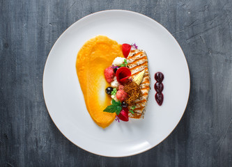Grilled turkey fillet with pumpkin puree and vegetables on white plate. Close view.