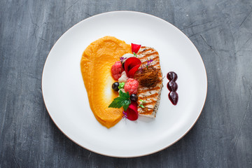 Grilled turkey fillet with pumpkin puree and vegetables on white plate. Close view.