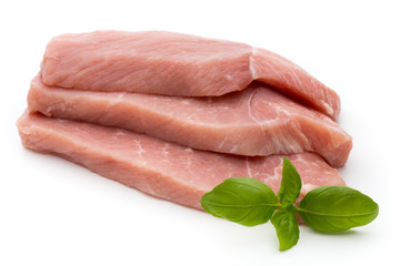 Fresh pork fillet with basil on a white background.