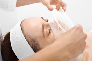Pielęgnacja skóry w klinice medycyny estetycznej. Kosmetyczka zdejmuje pacjentce bandaż z twarzy. - obrazy, fototapety, plakaty
