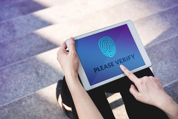 Verification Access for Security System Concept, Woman using Tablet with Fingerprint Scanning Technology in Outdoor