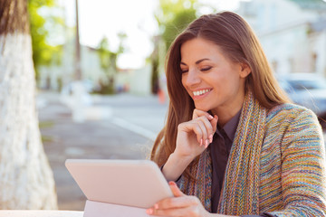 Smiling woman using her tablet outside on a city street background