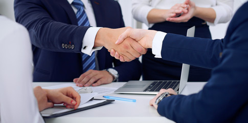 Business handshake at meeting or negotiation in the office, close-up. Partners are satisfied because signing contract or financial papers