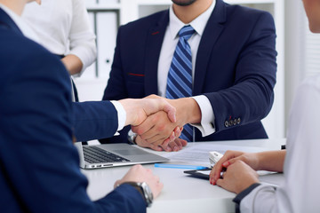 Business handshake at meeting or negotiation in the office, close-up. Partners are satisfied because signing contract or financial papers